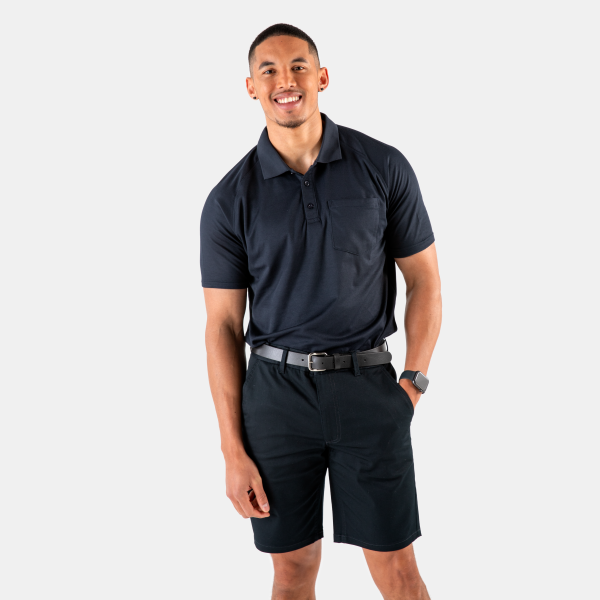 a Confident Man Smiles at the Camera, Wearing a Dark Navy Polo Shirt with a Pocket on the Left Chest and Matching Navy Chino Shorts by Designs to You.