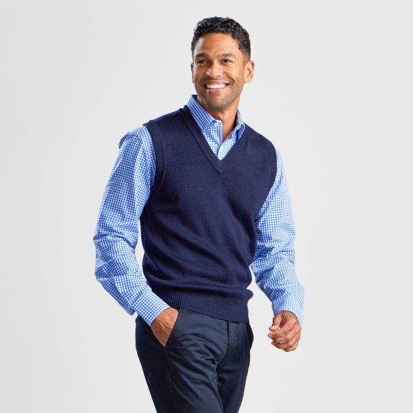 Man Smiling with a Navy V-neck Pullover Vest over a Checkered Shirt, with Hands in Trouser Pockets.