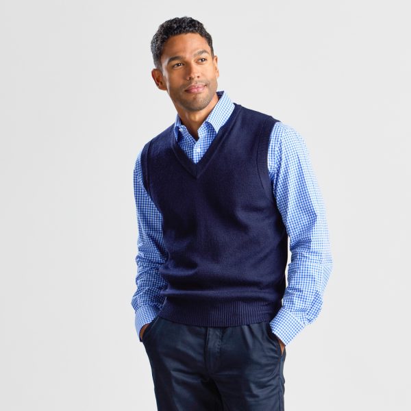 Man in a Navy V-neck Pullover Vest Looking to the Side, over a Checkered Button-up Shirt, with a Hand Casually in His Trouser Pocket.