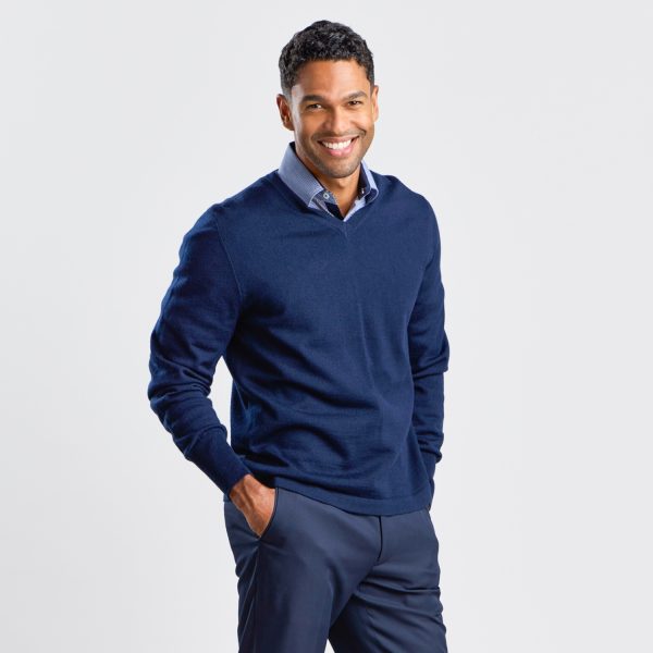 Man Casually Posing in a Navy V-neck Pullover, Partially Tucking His Hands into Trouser Pockets.