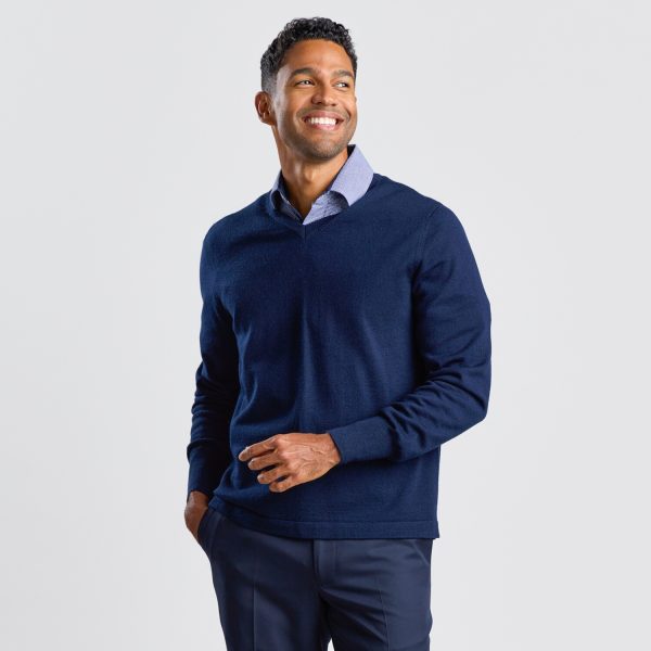 Front View of a Man in a Navy V-neck Pullover over a Patterned Button-up Shirt, Smiling and Looking to the Side.