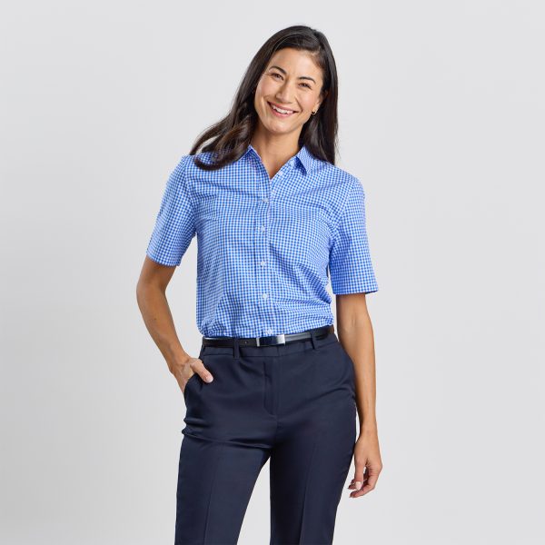 Front View of a Smiling Woman Wearing a Blue Checkered Short Sleeve Shirt Tucked into Navy Trousers.