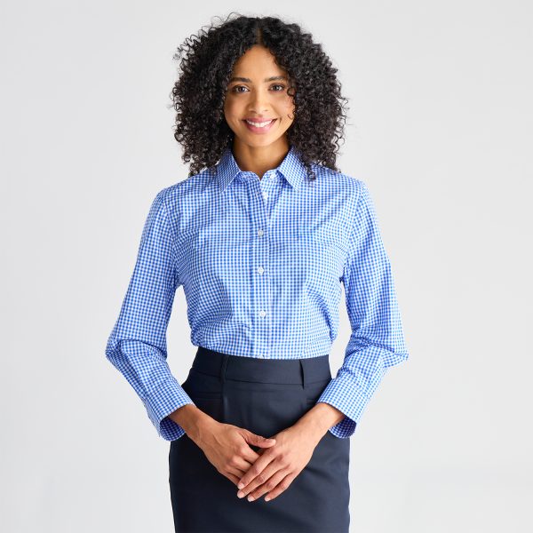 Front View of a Smiling Woman Wearing a Blue Checkered Long Sleeve Shirt Tucked into a Navy Skirt.