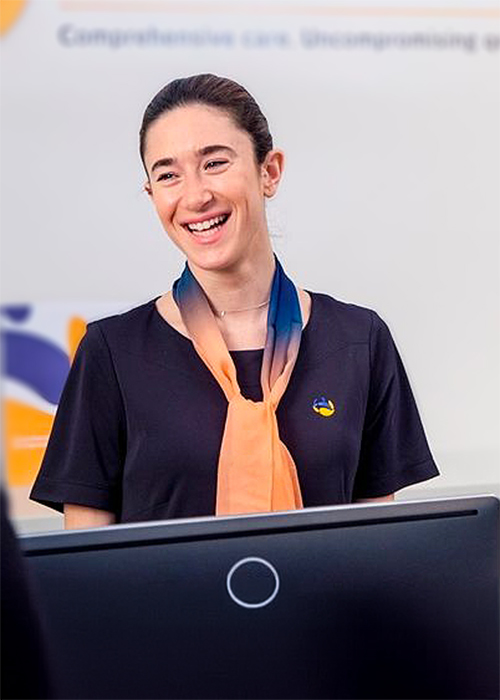 a Smiling Women Wearing an I-med Uniform & Scarf.