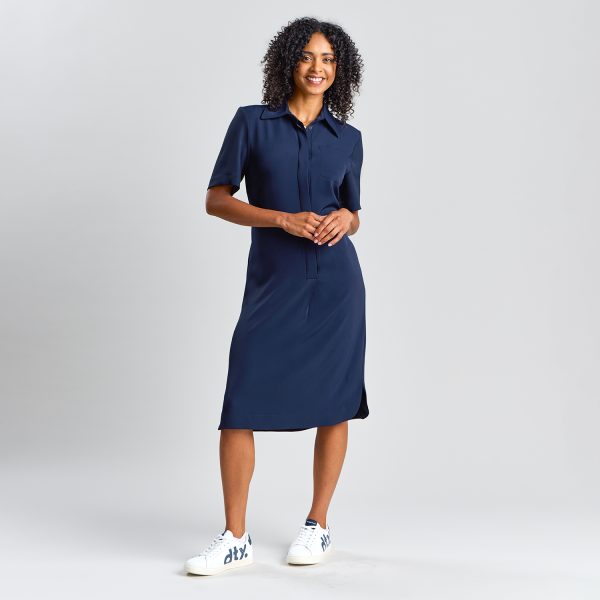 Woman Wearing a Short-sleeve, Button-up Navy Healthcare Shirt Dress with a Collar, Mid-length Hem, and Subtle Side Slits, Standing with Hands Clasped in Front.