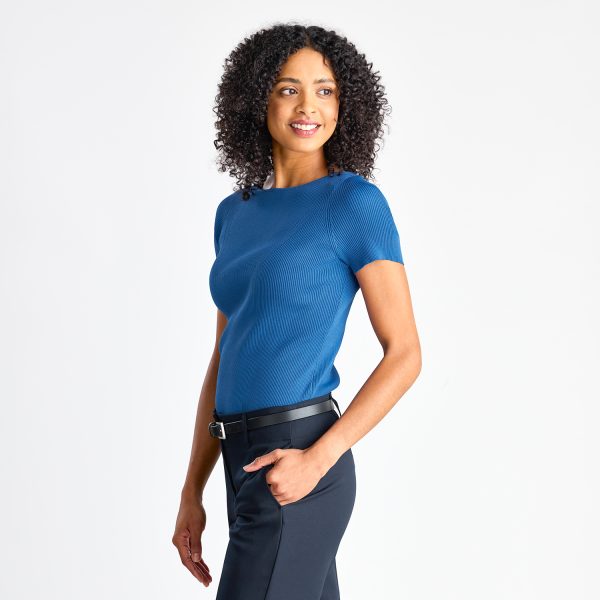 Side Angle of a Woman in a Blue Short Sleeve Milano Knit Boat Neck Top with Navy Trousers.