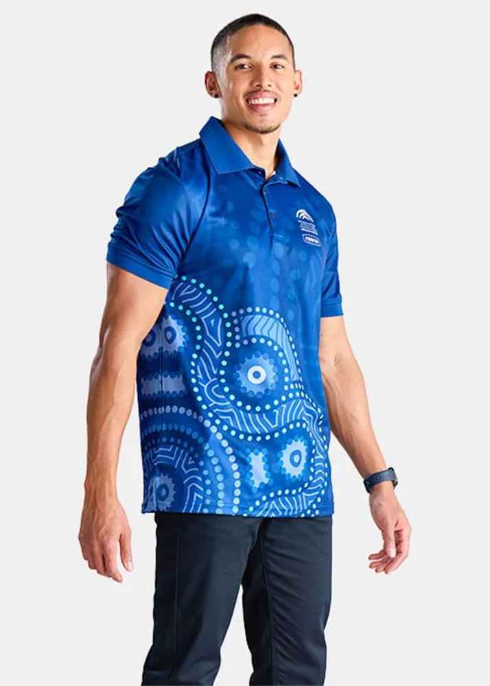 Man wearing a blue Reconciliation polo shirt with Indigenous artwork, featuring abstract dot and circular patterns on the lower half of the shirt.